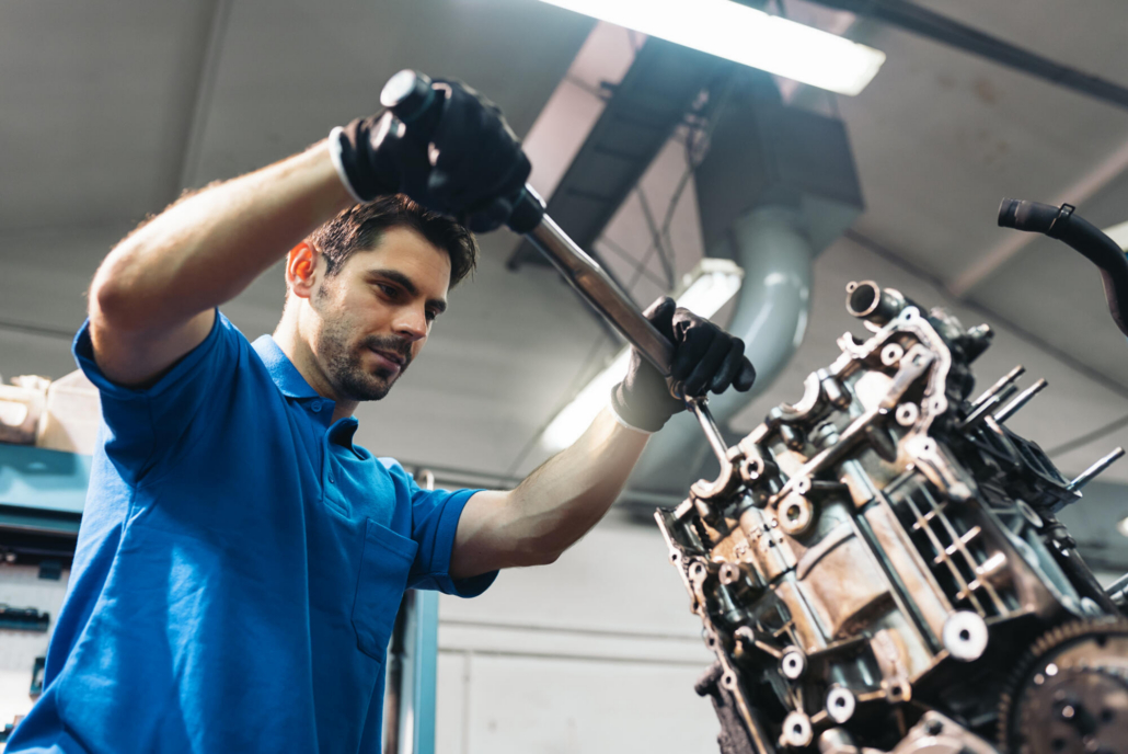mechanic with torque wrench working on engine
